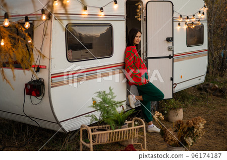Caucasian woman in oversized red knitted jumper travels in motorhome in autumn. Caucasian woman in oversized red knitted jumper travels in motorhome in autumn. 96174187