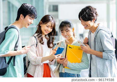 Male and female college students looking at smartphones Male and female college students looking at smartphones 96174586