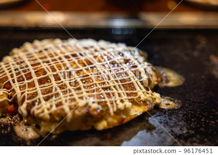Okonomiyaki cooked on an iron plate Okonomiyaki cooked on an iron plate 96176451