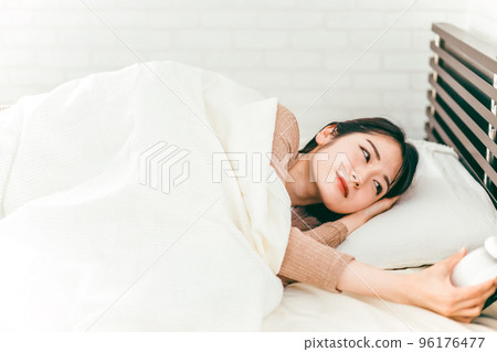 Japanese woman with low blood pressure who stops the alarm clock while sleepy and half asleep in bed 96176477