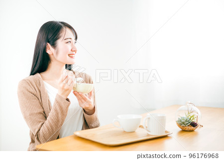 Smiling young Japanese woman eating yogurt for breakfast at home for diet 96176968
