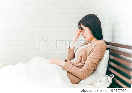 Japanese woman suffering from eye strain and headache in bedroom Japanese woman suffering from eye strain and headache in bedroom 96177614