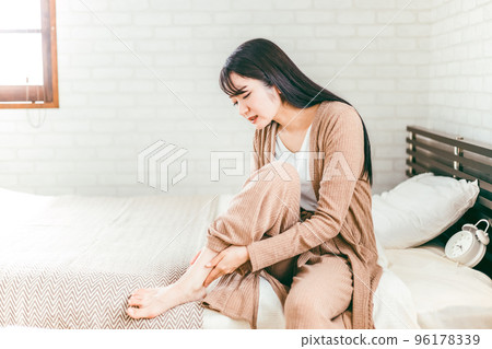 A woman whose ankle and Achilles tendon hurts in bed 96178339