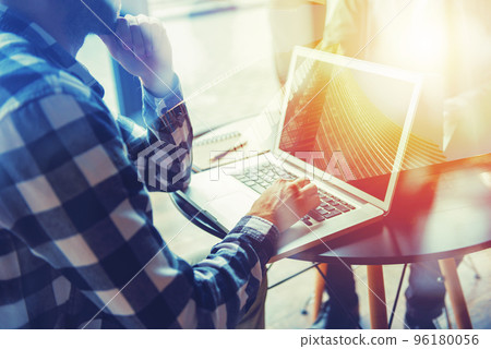 Business man works with laptop on a table in a modern office near window planning his future. Double exposure effect with a skyscraper Business man works with laptop on a table in a modern office near window planning his future. Double exposure effect with a skyscraper 96180056