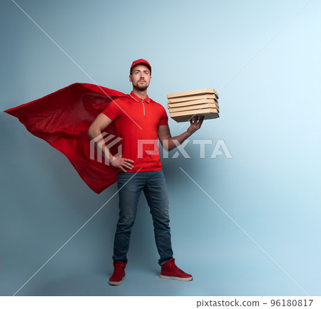 Deliveryman with pizzas acts like a powerful superhero. Concept of success and guarantee on shipment. Studio cyan background 96180817