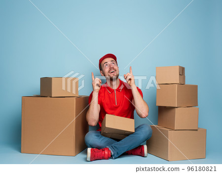 Courier is happy and indicates something above. Studio on cyan background 96180821