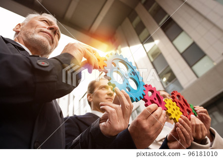 Business team connect pieces of gears. Teamwork, partnership and integration concept Business team connect pieces of gears. Teamwork, partnership and integration concept 96181010