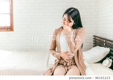 A Japanese woman suffering from abdominal pain, nausea, cough, and hyperemesis in bed 96181223