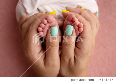 Mother is doing massage on her baby foot. Close up baby feet in mother hands on a pink background. Prevention of flat feet, development, muscle tone, dysplasia. Family, love, care, and health concept 96181257