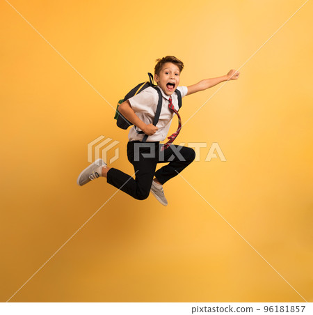Young boy student jumps high like a super hero. Yellow background 96181857