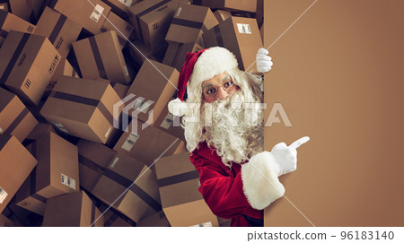 Santa Claus indicates a space for the Christimas present, with ready packages on background Santa Claus indicates a space for the Christimas present, with ready packages on background 96183140