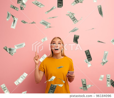 Blonde cute girl wins money with smartphone app. Amazed and surprised expression face. Pink background 96184096