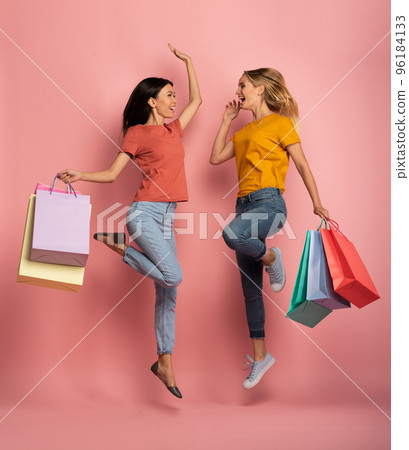 Two girls are happy after shopping. Joyful expression. Shop concept. Pink background 96184133