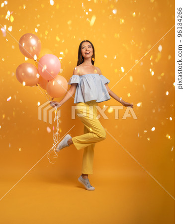Girl ready for a party with balloon. Joyful an happiness expression. Yellow background 96184266