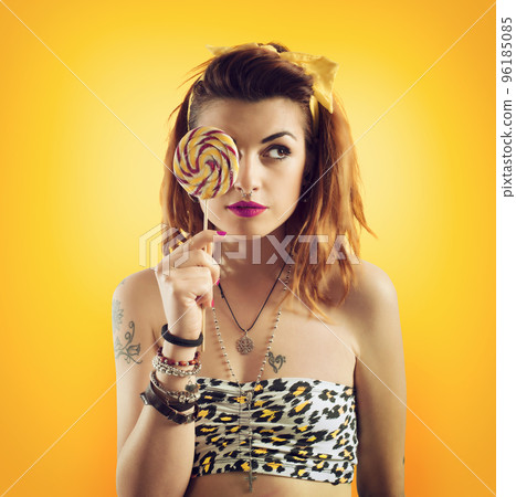 Young woman eating lollipop in yellow style Young woman eating lollipop in yellow style 96185085