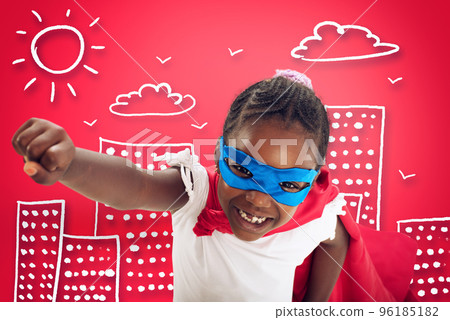 Child acts like a superhero to save the world on red background Child acts like a superhero to save the world on red background 96185182