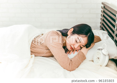 A woman in pajamas who does not wake up even when the alarm clock rings (sleepy / sleepy) A woman in pajamas who does not wake up even when the alarm clock rings (sleepy / sleepy) 96185803