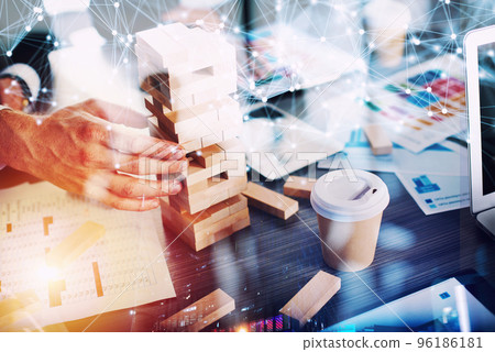 Business people build a tower of wooden bricks in the office. Concept of teamwork and partnership. double exposure with light effects 96186181