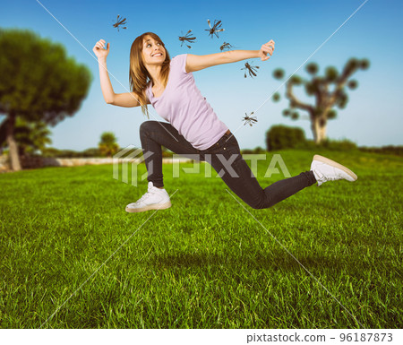 Woman defends herself from the attack of mosquitoes running fast 96187873