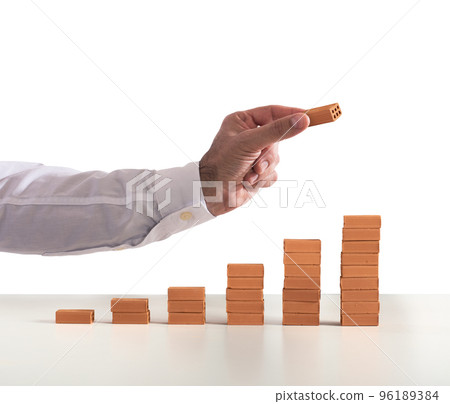 Businessman puts a brick on a bricks pile. Concept of growing statistics and success 96189384