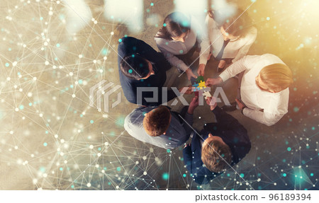 Business people join puzzle pieces in office. Concept of teamwork and partnership. double exposure with internet network effects Business people join puzzle pieces in office. Concept of teamwork and partnership. double exposure with internet network effects 96189394