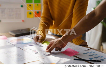UX developer and ui designer brainstorming about mobile app interface wireframe design with customer breif and color code at office. 96189819