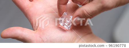 Person holds piece of ice on hands to cool skin 96190778