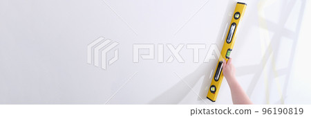 Person checks slope of wall with a water level closeup Person checks slope of wall with a water level closeup 96190819