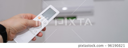 Person manual air conditioner with remote control closeup Person manual air conditioner with remote control closeup 96190821