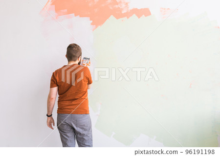 Young man using spatula and plastering of wall with white fresh finishing putty. Closeup. Repair work of home. Empty place for text. Side view. 96191198