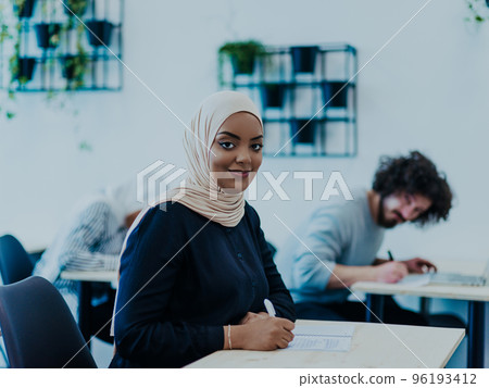 Photo of an African American Muslim woman being educated about business development in a modern classroom Photo of an African American Muslim woman being educated about business development in a modern classroom 96193412