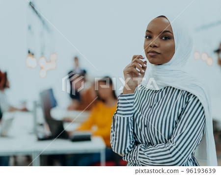 Portrait of a black african-american female muslim standing in a modern business office while wearing a hijab. Portrait of a black african-american female muslim standing in a modern business office while wearing a hijab. 96193639