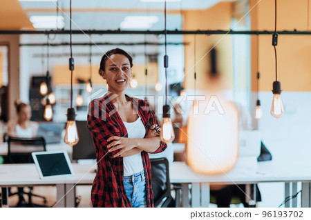 Female boss, manager executive posing in a modern startup office while being surrounded by her coworkers, team. Female boss, manager executive posing in a modern startup office while being surrounded by her coworkers, team. 96193702