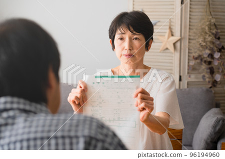 A middle-aged woman presenting a divorce notice to a middle-aged man Image of a middle-aged divorce 96194960