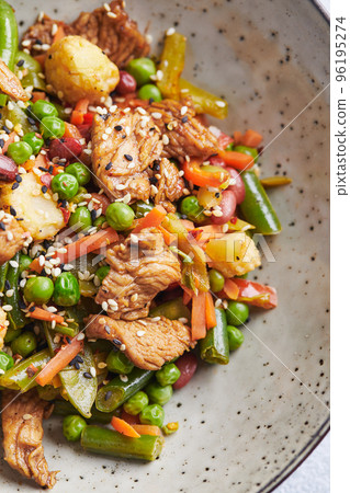 Wok with turkey meat, corn, green peas, green beans and carrots served on gray background. Asian food concept of street food 96195274