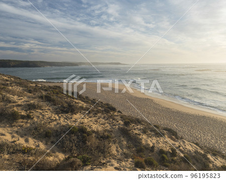 View of empty sand beach Praia do Farol at Vila Nova de Milfontes with view of ocean waves. Golden hour light View of empty sand beach Praia do Farol at Vila Nova de Milfontes with view of ocean waves. Golden hour light 96195823