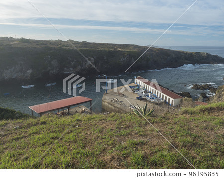 Rocky sea shore at wild Vicentina coast in Porto Covo with groups of fishermans boats anchored in a calm bay Rocky sea shore at wild Vicentina coast in Porto Covo with groups of fishermans boats anchored in a calm bay 96195835