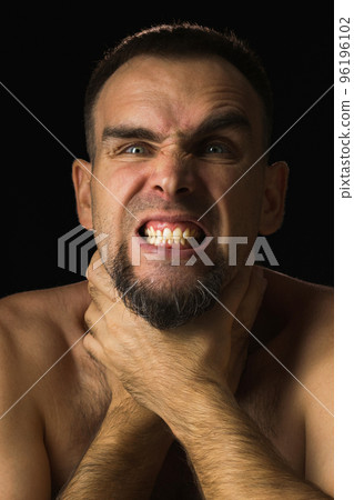 Bearded man squeezes his neck with his hands. Teeth clenched. Man makes suicide gesture, strangling himself. Portrait on black background. Bearded man squeezes his neck with his hands. Teeth clenched. Man makes suicide gesture, strangling himself. Portrait on black background. 96196102