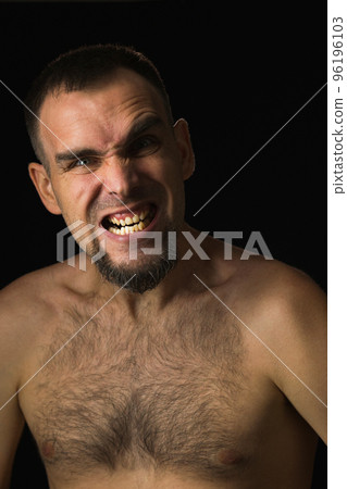 Portrait of an angry man with open mouth and frowning eyebrow. Caucasian man with shirtless beard on black background. Human emotions. Portrait of an angry man with open mouth and frowning eyebrow. Caucasian man with shirtless beard on black background. Human emotions. 96196103