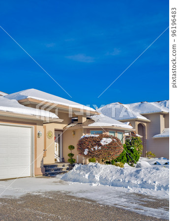Entrance of luxury house with driveway and front yard in snow 96196483