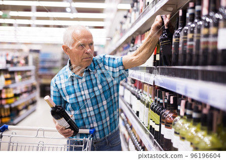 elderly retired senor buying wine in the alcohol section of the supermarket 96196604
