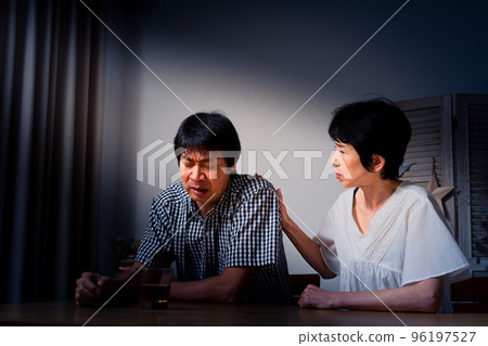 A middle man with his head down at home and a middle woman comforting him 96197527