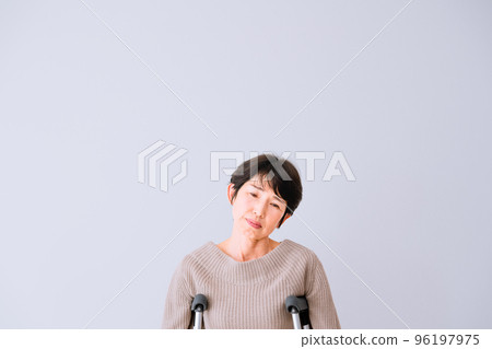 A middle-aged woman on crutches with an anxious expression Medical insurance image 96197975