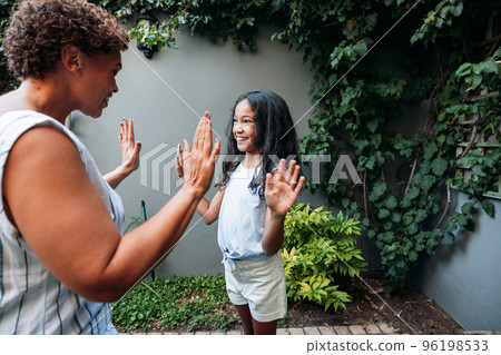 Happy girl and her grandma playing outdoors Happy girl and her grandma playing outdoors 96198533
