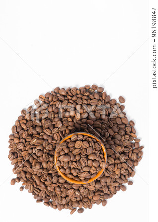 A small saucer with coffee beans stands on a pile of coffee on a white background. 96198842