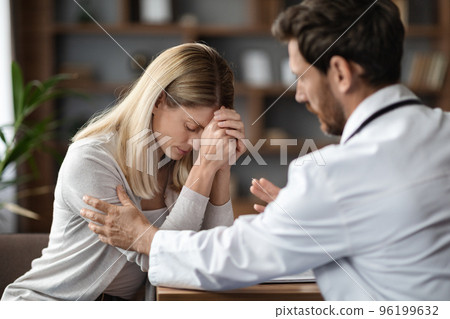 Therapist Man Comforting Upset Female Patient During Meeting In Clinic Therapist Man Comforting Upset Female Patient During Meeting In Clinic 96199632