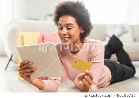 Happy millennial african american lady with many packages with purchases shows credit card 96199715