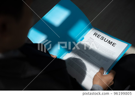 Unemployed man apply for a job sitting in queue holding resume papers  waiting for job interview with sun light and shadow. 96199805