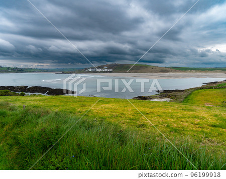 View of Clonakilty Bay. Thick grass near the sea. The coastline of the south of Ireland. Seaside landscape. Cloudy weather before a thunderstorm. 96199918