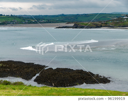 View of Clonakilty Bay on a cloudy day. Thick grass near the sea. The coastline of the Ireland. Seaside landscape. Cloudy weather. View of Clonakilty Bay on a cloudy day. Thick grass near the sea. The coastline of the Ireland. Seaside landscape. Cloudy weather. 96199919
